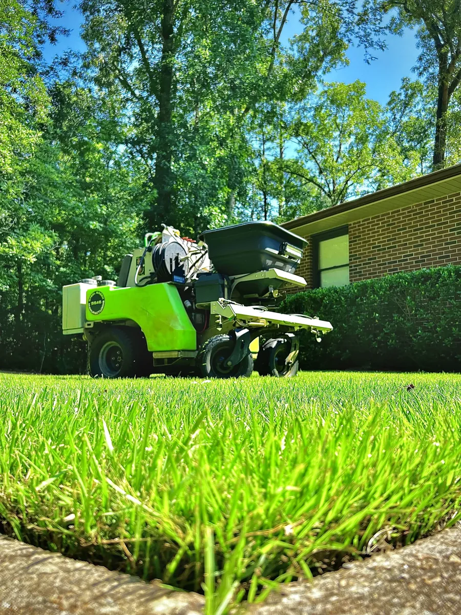 A close view of healthy grass with Pro Turf treatment equipment in the background