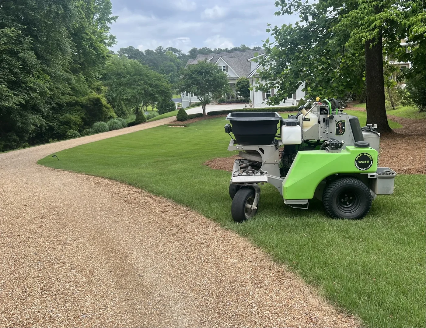 Lawn treatment equipment beside a landscaped driveway.